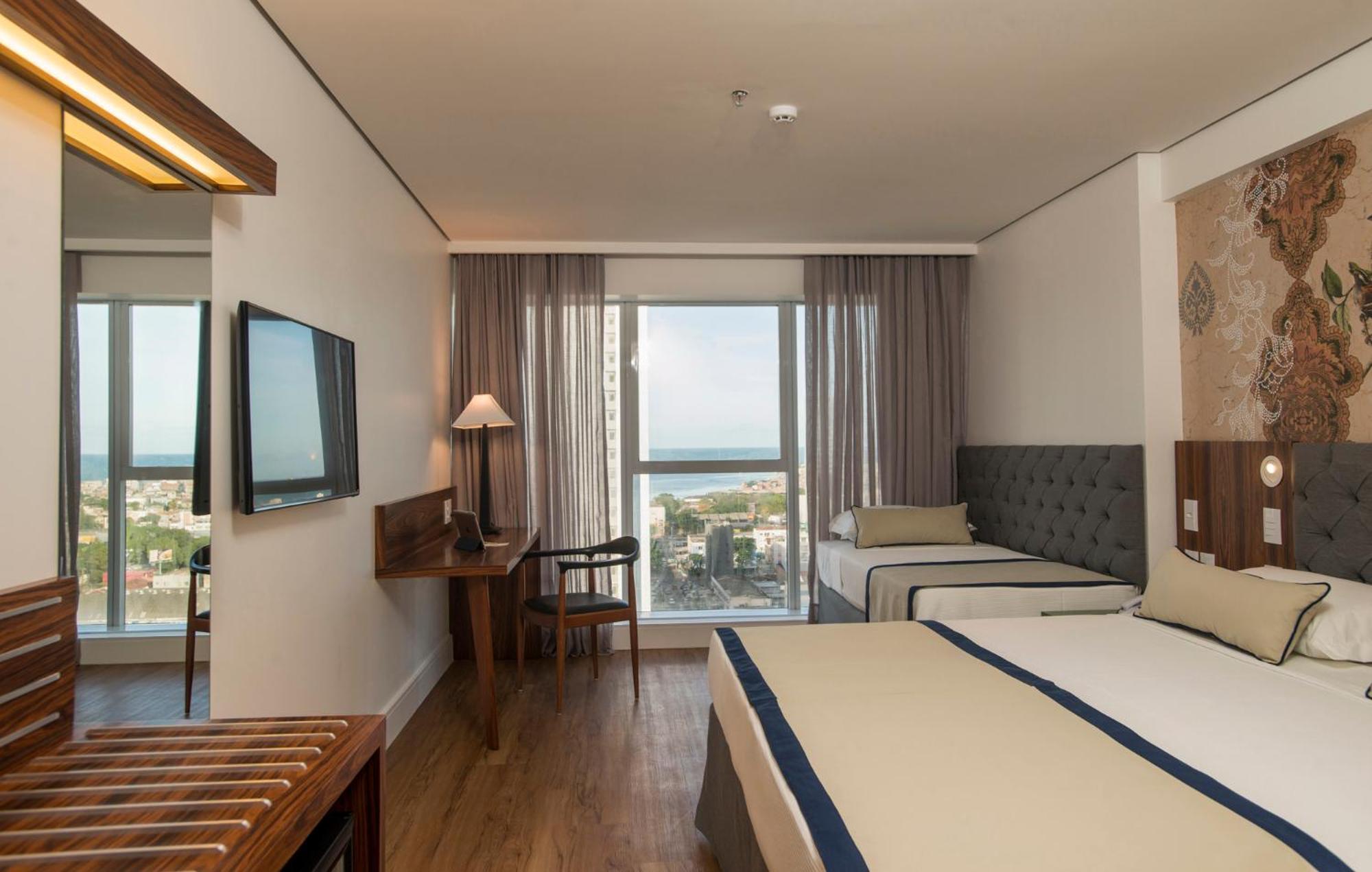 Hotel Luzeiros ريسيفي المظهر الخارجي الصورة The photo shows a hotel room that features a modern and comfortable design. There are two beds: one larger bed and a smaller twin bed. The room has large windows with curtains that allow natural light to enter, offering a view of the outside, possibl
